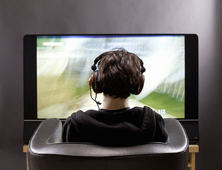 student facing large screen television with headphones on