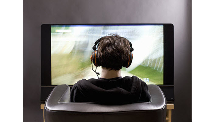 student facing large screen television with headphones on